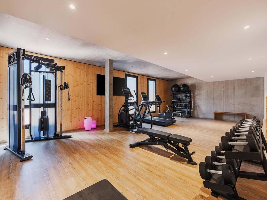 Een sportschool met trainingsapparatuur, houten wanden en een betonnen plafond.