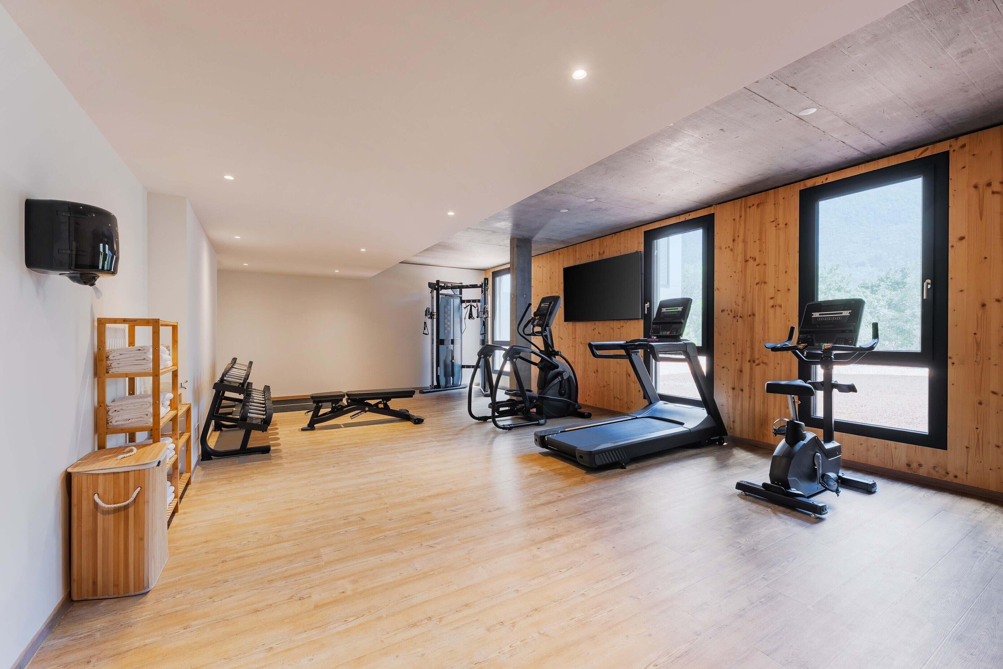 Une salle de sport équipée de matériel d’exercice, dotée d’un plancher en bois et de grandes fenêtres.