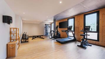 Une salle de sport équipée de matériel d’exercice, dotée d’un plancher en bois et de grandes fenêtres.