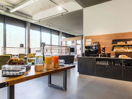 Un café moderno con una mesa de madera alargada, dispensadores de jugo y una estación de café.