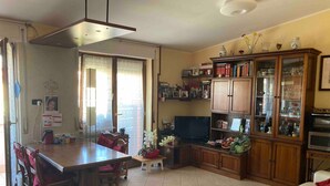 A living room with a dining area, a TV, and a cabinet with glass doors. - Apartment 'Teresa Al Mare' with Balcony, Wi-Fi and Air Conditioning (Montesilvano)
