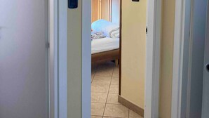 A hallway leading to a bedroom with a bed, wooden wardrobe, and a tiled floor. - Apartment 'Teresa Al Mare' with Balcony, Wi-Fi and Air Conditioning (Montesilvano)