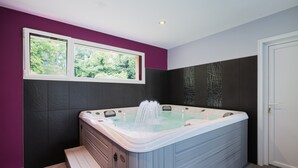 A modern bathroom with a large bathtub, a window with a view of greenery, and a door. - Holiday Home 'La Clémençaie' with Private Terrace, Garden and Wi-Fi (Réminiac)