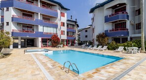Un hotel con piscina, mobiliario exterior y fachada con baldosas.