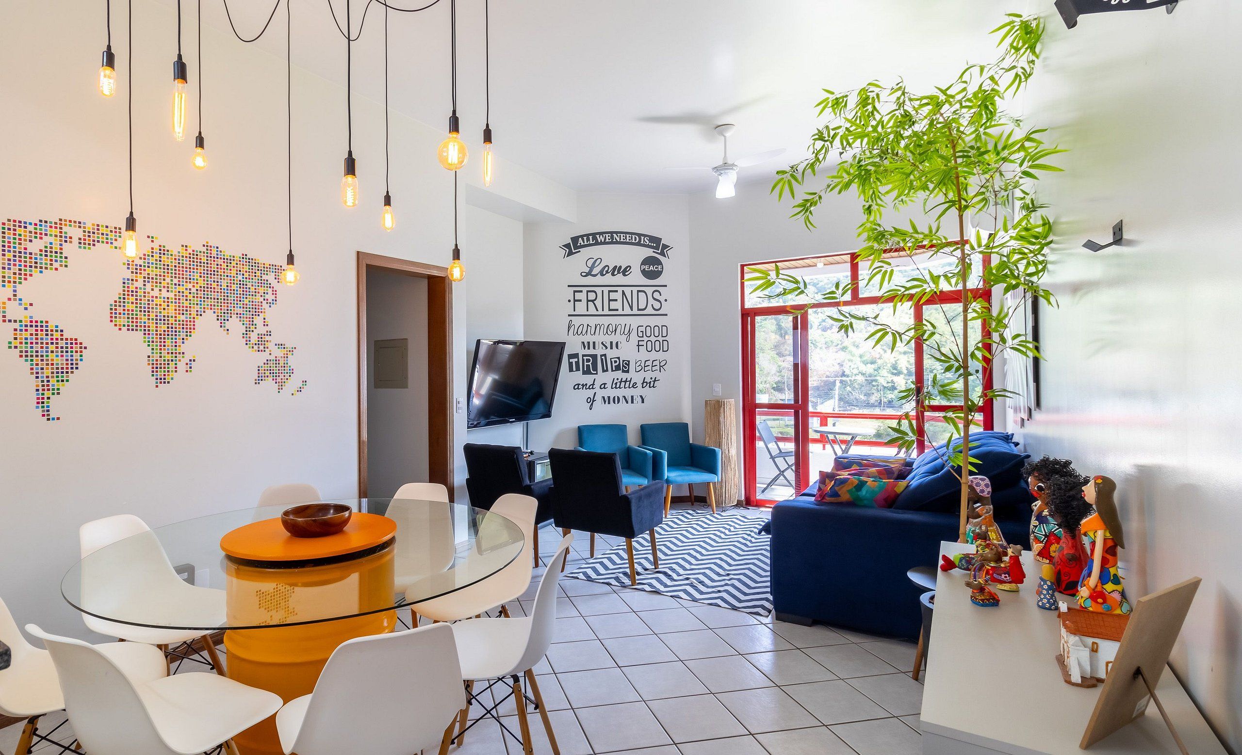 Una sala moderna con una mesa de comedor de vidrio, sillas blancas, un sofá azul y una planta decorativa.