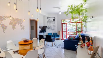Una sala moderna con una mesa de comedor de vidrio, sillas blancas, un sofá azul y una planta decorativa.