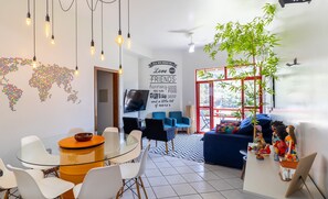 Una sala moderna con una mesa de comedor de vidrio, sillas blancas, un sofá azul y una planta decorativa.