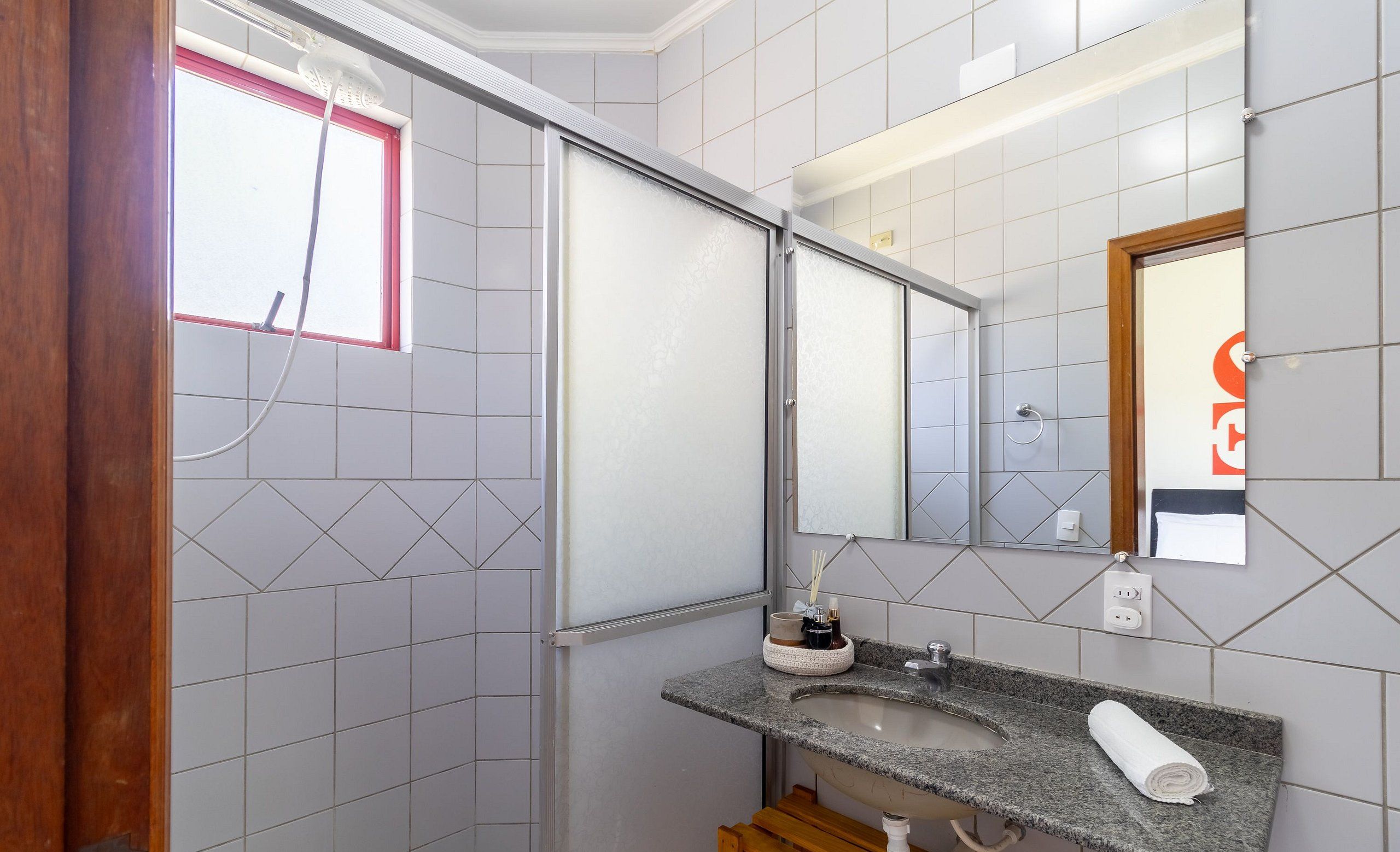 A bathroom with a shower, a sink with a towel, and a mirror.