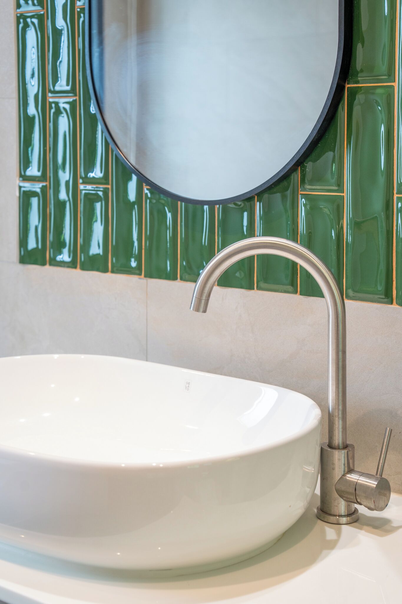 A bathroom with a white sink, a modern faucet, and a mirror.