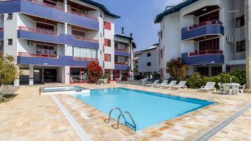 A hotel with a swimming pool, outdoor seating, and a tiled exterior.