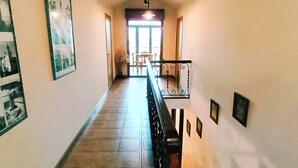 A hallway with a staircase, tiled floor, and framed pictures on the walls. - CASONA LA ZAMPUCA (Gijón)