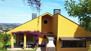 A yellow house with a patio, outdoor seating, and a stone fireplace. - CASONA LA ZAMPUCA (Gijón)