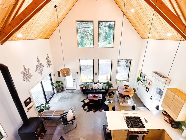 Una cocina amplia con una isla central, un comedor con mesa de madera y una sala de estar con sofá negro.