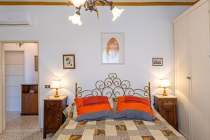 A bedroom with a bed, two bedside tables with lamps, a ceiling light fixture, and a door.