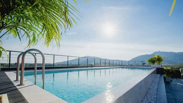 A swimming pool with a clear view of the mountains in the background. - C212 NOON Village (Chalong)