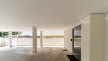 A spacious indoor area with a concrete floor, white walls, and a glass door leading to an outdoor balcony.
