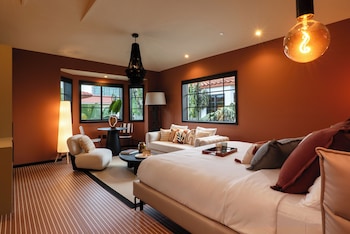 An outdoor patio area with green and white checkered chairs and tables, surrounded by lush tropical plants and a staircase leading to an upper level. at Maison Felix