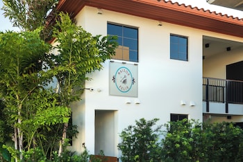 A paved pathway lined with palm trees and greenery, leading to a fenced area. at Maison Felix