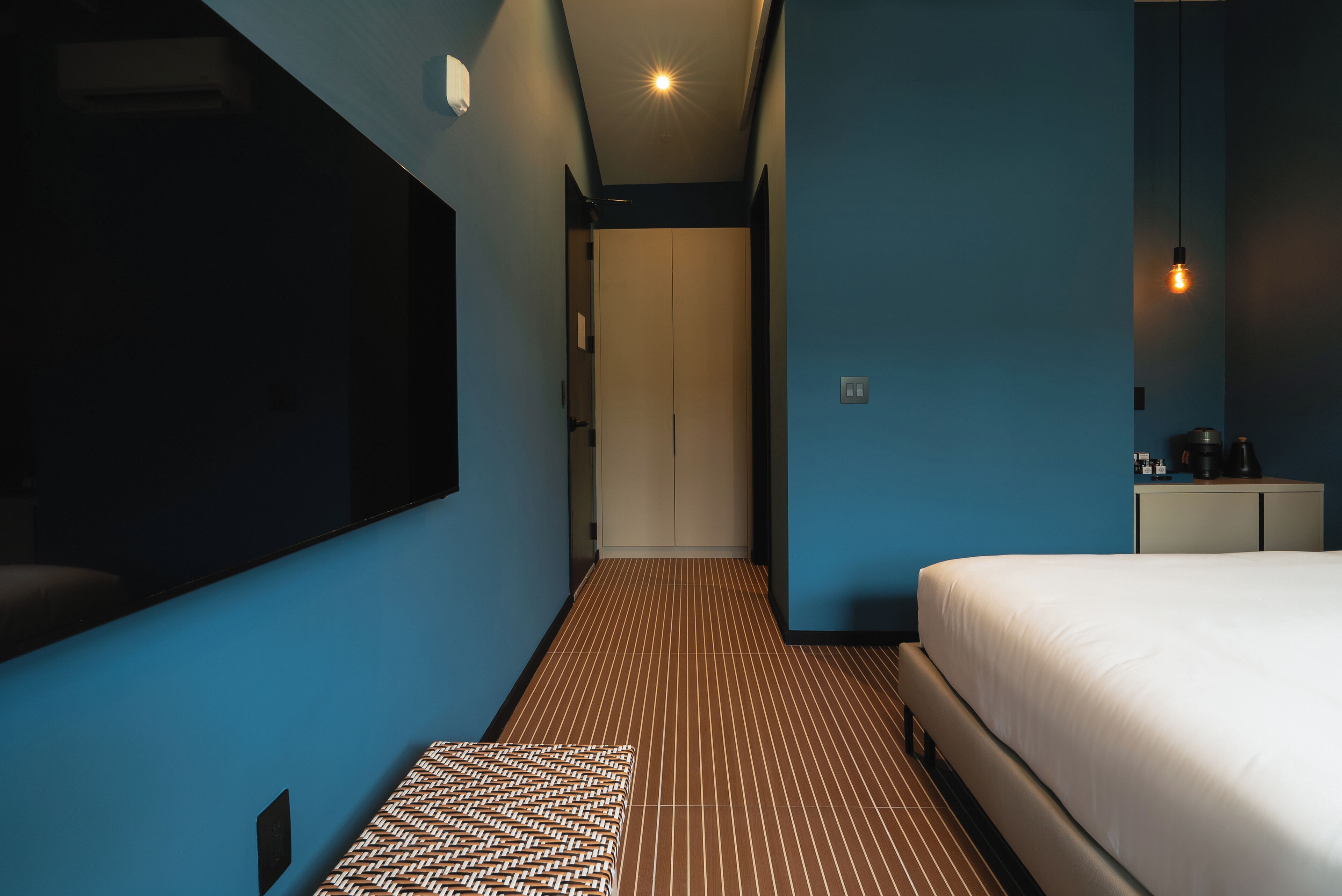 Habitación de hotel con una cama grande, televisión de pantalla plana, mesita de noche y alfombra estampada.