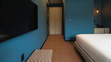 Habitación de hotel con una cama grande, televisión de pantalla plana, mesita de noche y alfombra estampada.