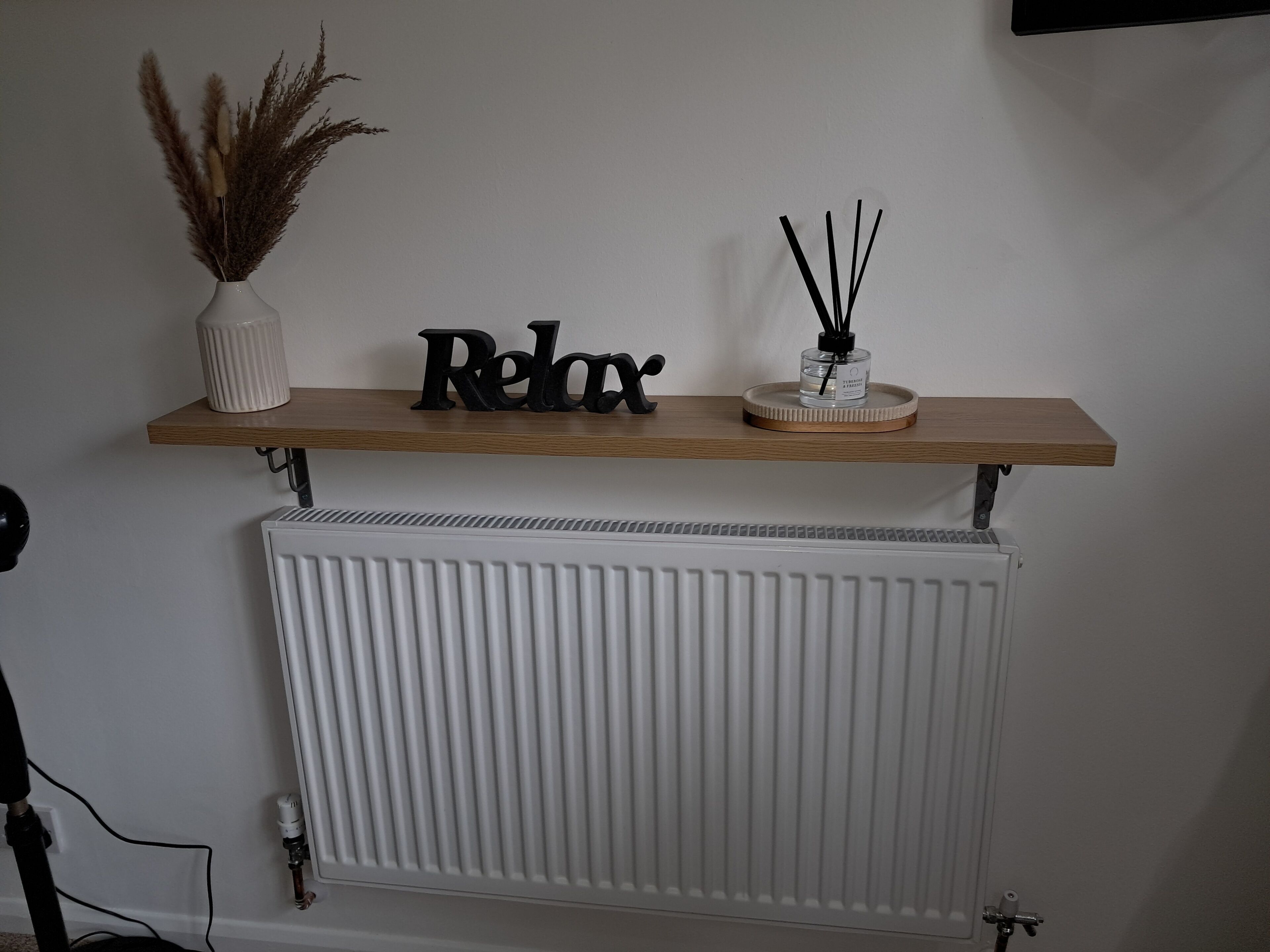 A shelf with decorative items and a radiator below.