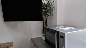 A modern kitchen with a built-in microwave, a wooden shelf, and a potted plant.