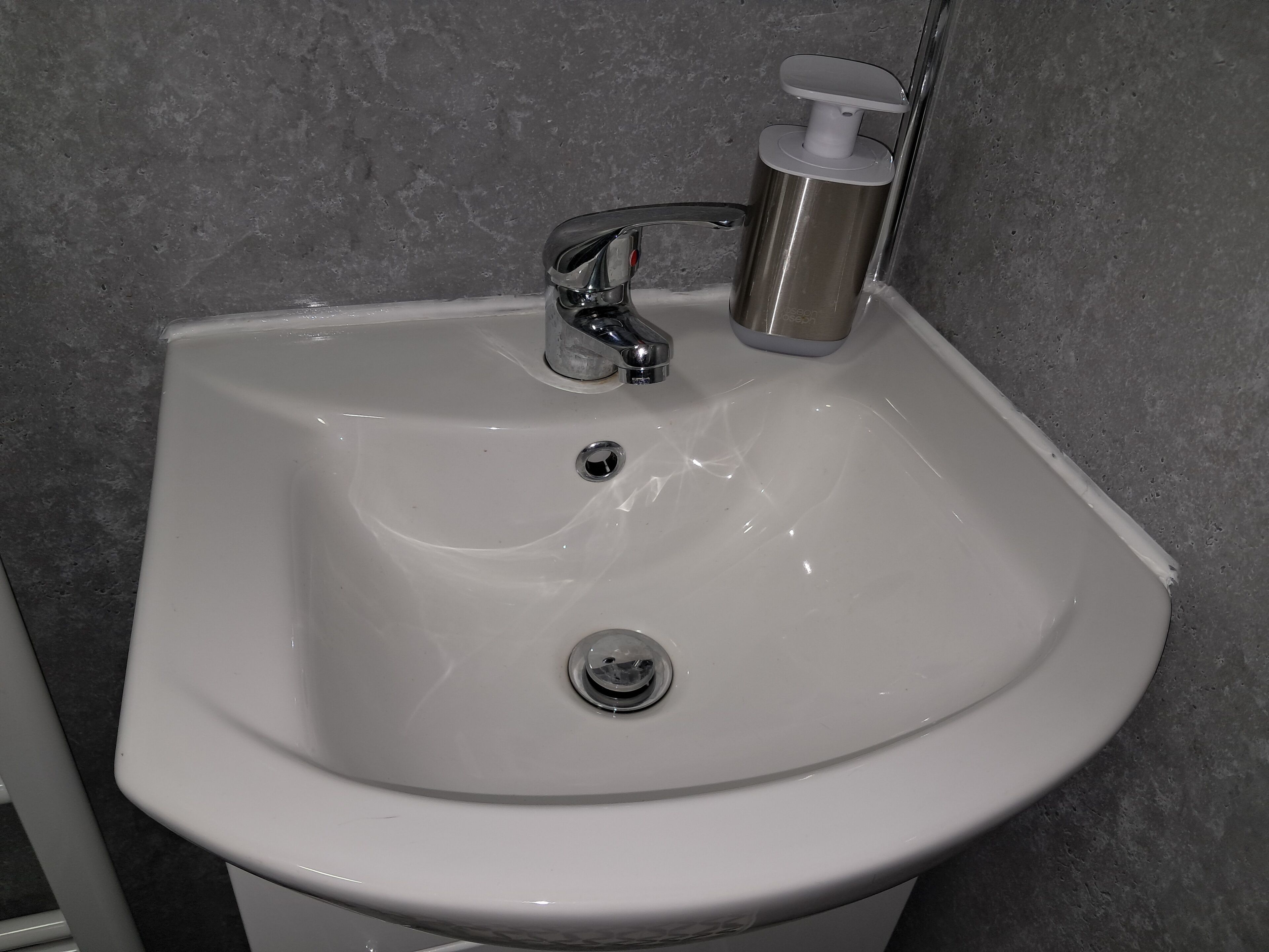 A white bathroom sink with a chrome faucet and soap dispenser.