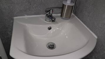 A white bathroom sink with a chrome faucet and soap dispenser.