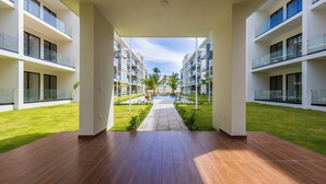 A modern hotel corridor with a pool view, glass railings, and a tiled floor.