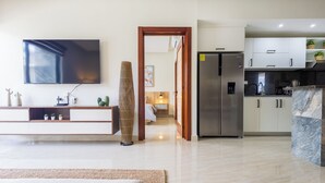 A modern kitchen with a built-in refrigerator, a flat-screen TV, and a dining area with a marble island.