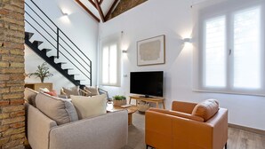 Una sala de estar moderna con sofá, sillón y televisor de pantalla plana.