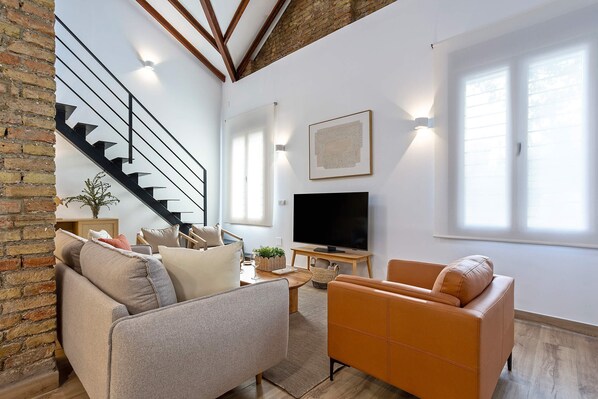 Una sala de estar moderna con sofá, sillón y televisor de pantalla plana.