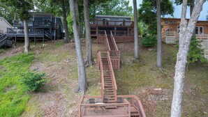 Un escalier en bois mène à une cabane dotée d’un garage, le tout étant entouré d’arbres.