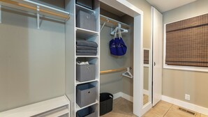 Un dressing avec plusieurs étagères, une tringle à vêtements et une porte donnant sur une autre pièce.