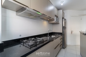 Una cocina moderna con estufa a gas, electrodomésticos de acero inoxidable y armarios blancos.