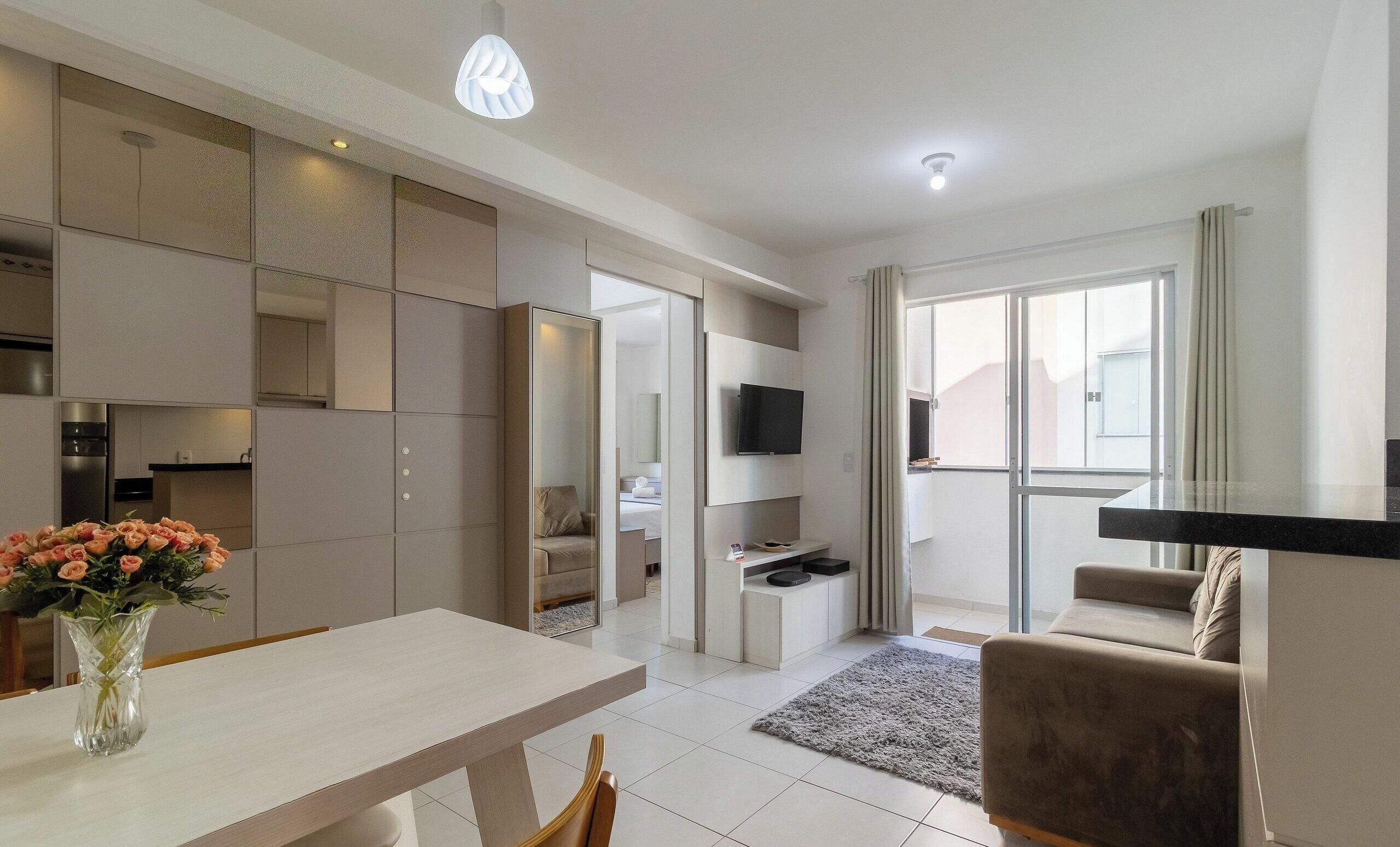 A modern living room with a dining area, a kitchen, and a balcony with a TV.