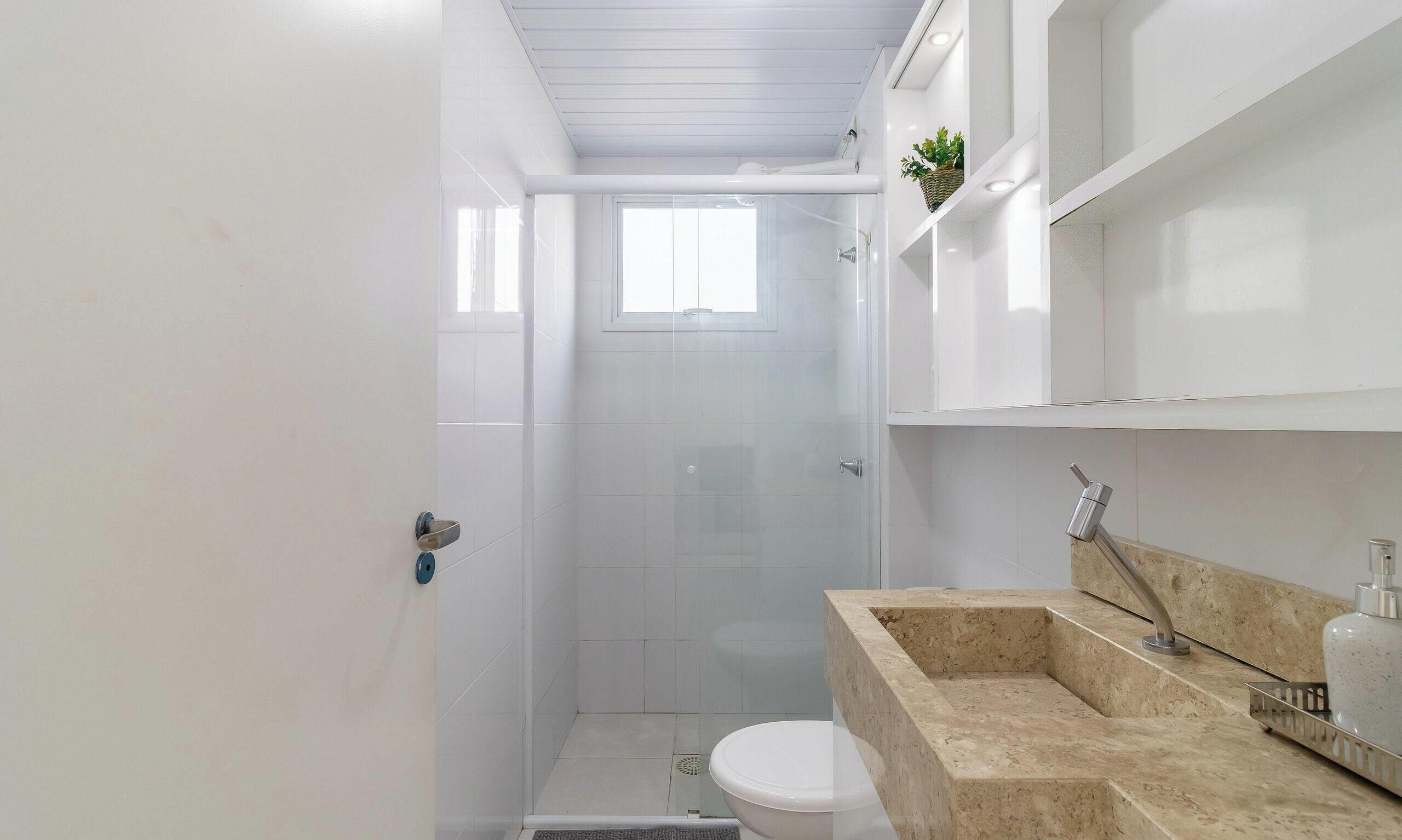 A compact bathroom with a shower, toilet, and a sink with a marble countertop.