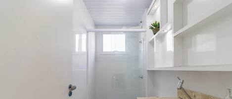 A compact bathroom with a shower, toilet, and a sink with a marble countertop.