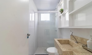 Un baño moderno con ducha, inodoro e lavabo de mármol.