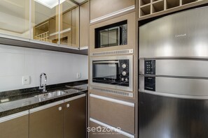 A modern kitchen with stainless steel appliances, a built-in microwave, and a double sink. - Apt. w/ Barbecue & Pool in Canasvieiras Rpc0305 (Florianópolis)