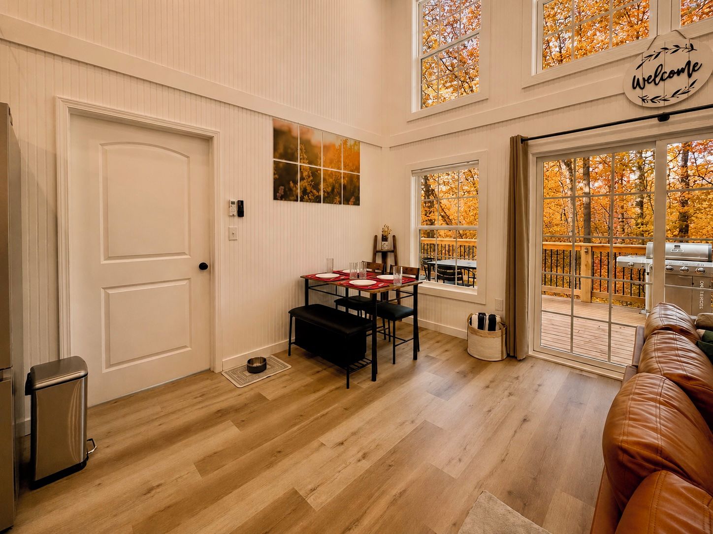A dining area with a table set for four, a black bench, and a grill outside.