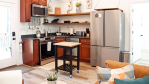 A modern kitchen with wooden cabinets, stainless steel appliances, and a central island. - Acorn Drop • 2 Full Baths • Hot Tub • <10 Min RRG (Campton)