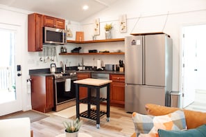 A modern kitchen with wooden cabinets, stainless steel appliances, and a central island. - Acorn Drop • 2 Full Baths • Hot Tub • <10 Min RRG (Campton)
