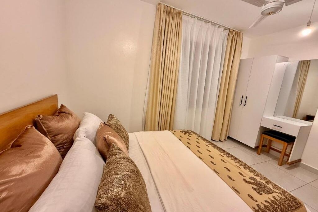 A bedroom with a bed, a bedside table, a wardrobe, and a mirror.