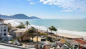 A coastal view with a beach, buildings, and a mountain in the background. - Modern ap W/pool one Block From the Beach Rmi201 (Florianópolis)