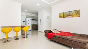 A modern living room with a brown sofa, a red throw blanket, and three yellow chairs. - Modern ap W/pool one Block From the Beach Rmi201 (Florianópolis)