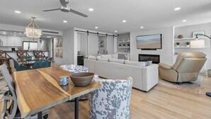 Ein modernes Wohnzimmer mit einem Holzesstisch, einem weißen Sofa und einem beige farbenen Liegesessel.