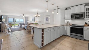 A spacious kitchen with white cabinetry, a large island, and a view to the outdoors.