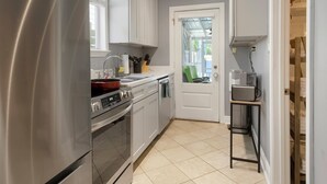 Et moderne køkken med rustfrie hårde hvidevarer, flisegulv og en dør til en balkon.
