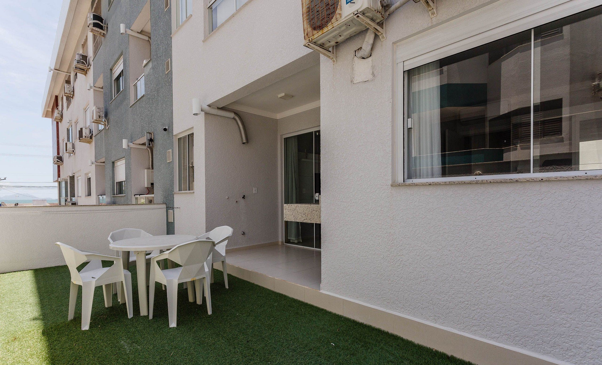 A modern building with a balcony, outdoor seating, and a view of the sea.
